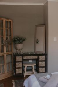 a bedroom with a dresser with a mirror and a stool at Villa Rose Guesthouse & Venue in Bloemfontein