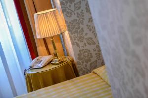 a lamp on a table next to a bed with a phone at Albergo Alla Posta in Trieste