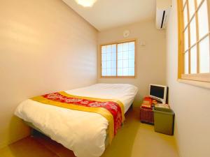 um pequeno quarto com uma cama e uma janela em Hachi Kamakura KOIWA em Tóquio