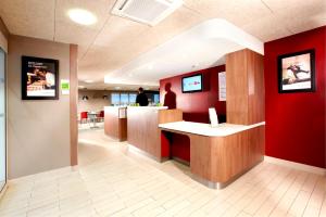 a waiting room with a counter and red walls at Campanile Lille Nord Wasquehal in Wasquehal