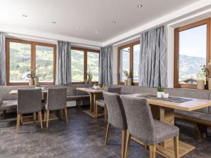 uma sala de jantar com mesas, cadeiras e janelas em Moiklerhof holiday home in Ramsau im Zillertal em Ramsau im Zillertal