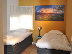 1 dormitorio con 2 camas y un cuadro en la pared en Bungalow close to seaside resort De Koog en Westermient