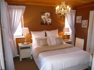 a bedroom with a bed with white sheets and a chandelier at Berghaven in Underberg