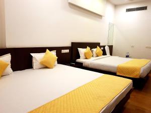 Hotel Vasudha Palace في جايبور: سريرين في غرفة الفندق مع وسائد صفراء