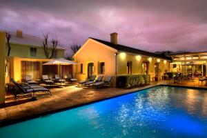 a swimming pool in front of a house at night at The Portswood Hotel in Cape Town