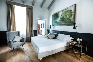 a bedroom with a large bed and a chair at Soprarno Suites in Florence