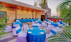 a banquet hall with blue tables and white chairs at Treebo Grand Euro Pipliyahana Square in Indore