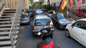 a row of parked cars and a scooter on a street at Hotel Boccascena in Genoa