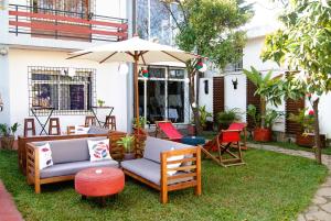a patio with chairs and an umbrella on the grass at Villa Mahefa - WIFI - Canal Plus - Terrasse & Jardin in Antananarivo