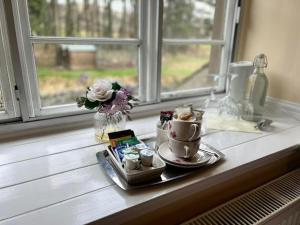 a tray with two cups and a vase with flowers on a window at Dunscar Farm Bed & Breakfast in Castleton