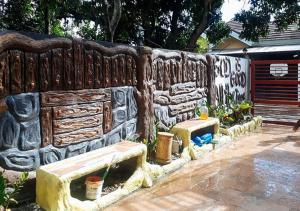 una pared de piedra con dos bancos delante en RedDoorz @ Balay Hiraya Apartment, en Tabao