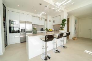 kuchnia z białymi szafkami i blatem z barowymi stołkami w obiekcie Holiday in ground floor apartment in Marbella Club Hills, Benahavis w mieście Benahavís