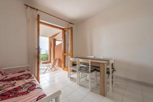a room with a table and a bed and a balcony at Casa delle Poiane Costa Rei in Monte Nai