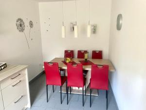 a dining room with a table and red chairs at FeWo Lüttje Wooge Dornum in Dornum