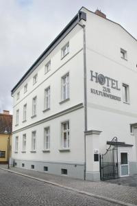 a white building with a hotel sign on it at Hotel zur Kulturweberei in Finsterwalde
