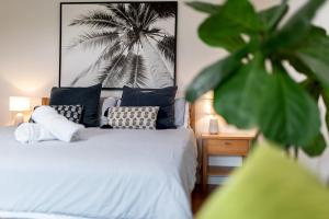 a bedroom with a bed with pillows and a palm tree at Tallows Studio -Modern, tranquil, dog friendly,2 mins to the beach in Suffolk Park