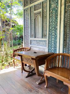 - une table en bois et 2 chaises sur une terrasse couverte dans l'établissement Sapulidi Cafe, Gallery & Resort, à Lembang