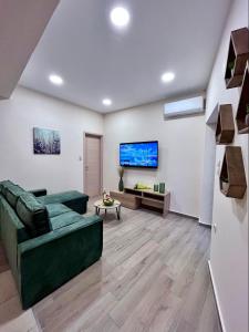 un soggiorno con divano verde e TV di Minos Studios a Chania