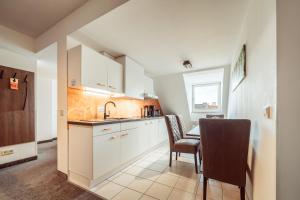 a kitchen with white cabinets and a table and chairs at Familienapartment Am Neumarkt lll in Dresden