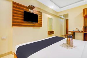 1 dormitorio con 1 cama y TV en la pared en Hotel Mina International, en Bombay