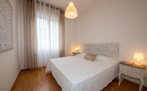 Un dormitorio blanco con una cama blanca y una ventana en Condominio Sirene, en Lido di Jesolo