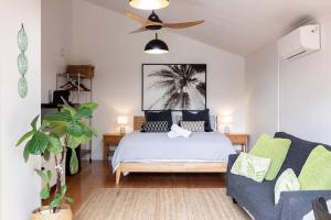 um quarto com uma cama, um sofá e uma ventoinha de tecto em Tallows Studio -Modern, tranquil, dog friendly,2 mins to the beach em Suffolk Park