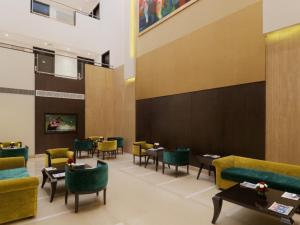 un restaurante con muebles verdes, mesas y sillas en Inde Hotel Vista Woods Huda City Centre, Gurgaon, en Gurgaon
