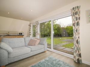 a living room with a couch and a sliding glass door at Lodge 22, Bodmin Holiday Park, Cornwall in Lanivet