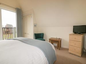 a bedroom with a bed and a television and a chair at Lodge 22, Bodmin Holiday Park, Cornwall in Lanivet