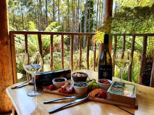 a table with a bottle of wine and two glasses at Lemonthyme Wilderness Retreat in Moina