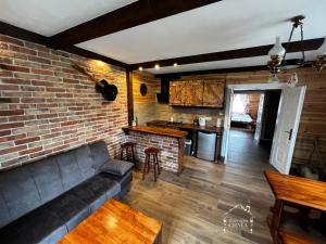 a living room with a couch and a brick wall at Bieszczady Noclegi "Muzyczna Chata" in Olszanica