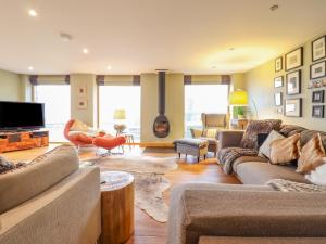 a living room with couches and a flat screen tv at Ty Gwyn Cottage in Llysfaen