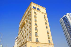 un edificio alto amarillo con un cielo azul en el fondo en Tariq Almoayed Tower, en Manama