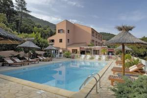 a swimming pool with chairs and umbrellas next to a building at Résidence Stella Marina in Serriera