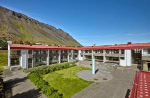 ein Gebäude mit rotem Dach und einem Innenhof mit Gras in der Unterkunft Hótel Torfnes in Ísafjörður