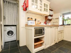 uma cozinha com uma máquina de lavar roupa e um micro-ondas em Gurnard's Cottage em Treen