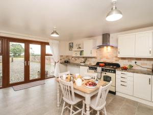 uma cozinha com uma mesa e cadeiras numa cozinha em Bramblewood Cottage 