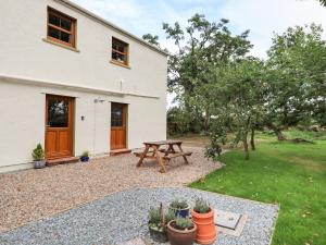 un patio avec une table de pique-nique devant une maison dans l'établissement Bramblewood Cottage, à Crookdake