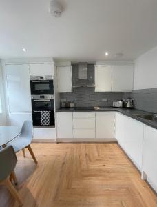 Il comprend une cuisine avec des placards blancs et du parquet. dans l'établissement Prosper House Apartments, à Norwich