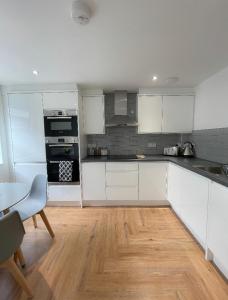 a kitchen with white cabinets and a wooden floor at Prosper House Apartments in Norwich +16 photos