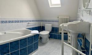 a bathroom with a tub and a toilet and a sink at Hotel Le Normand in Houlgate