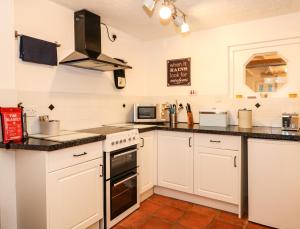 a kitchen with white cabinets and a stove top oven at Duck Cottage in Snettisham