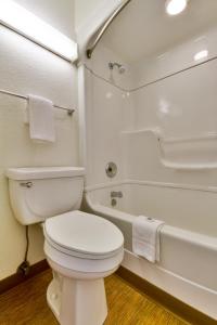 a white bathroom with a toilet and a bath tub at Motel 6-Irving, TX - Dallas in Irving