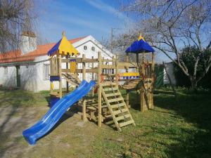 um parque infantil de madeira com um escorrega e um guarda-chuva em Quinta da Torre em Torre