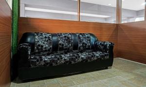 ein schwarzes Sofa in einem Zimmer mit einer Holzwand in der Unterkunft Treebo Trend Atithi Corporate Stay Baner Baner IT Hub in Pune