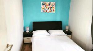 ein Schlafzimmer mit einem weißen Bett und einer blauen Wand in der Unterkunft Apartman Maslineo in Maslinica