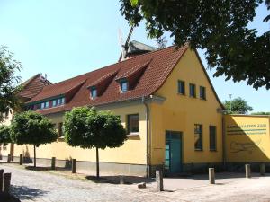 un edificio giallo con tetto marrone di Ferienwohnung B Gästehaus Mühlenstein a Bad Sülze
