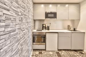 una cocina con armarios blancos y una pared de ladrillo en 04 Best Flat Montorgeuil 3, en París