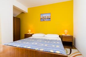 een slaapkamer met een bed met een gele muur bij Guesthouse Moretic in Orasac