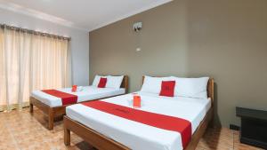 a bedroom with two beds with red and white sheets at RedDoorz @ Balay Hiraya Apartment in Tabao